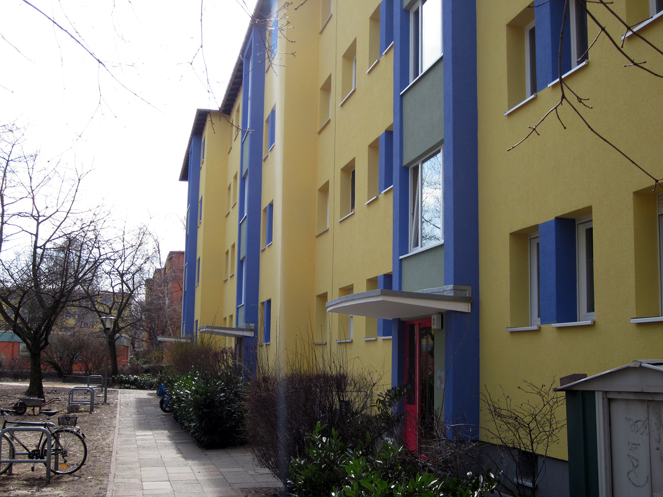 Gelbes Wohngebäude mit blauen Streifen und Balkonen