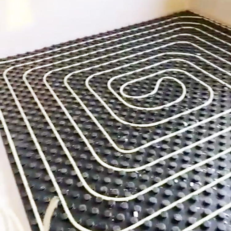 Schwarze Fußbodenheizungsmatten mit weißen Rohren in Spiralmuster