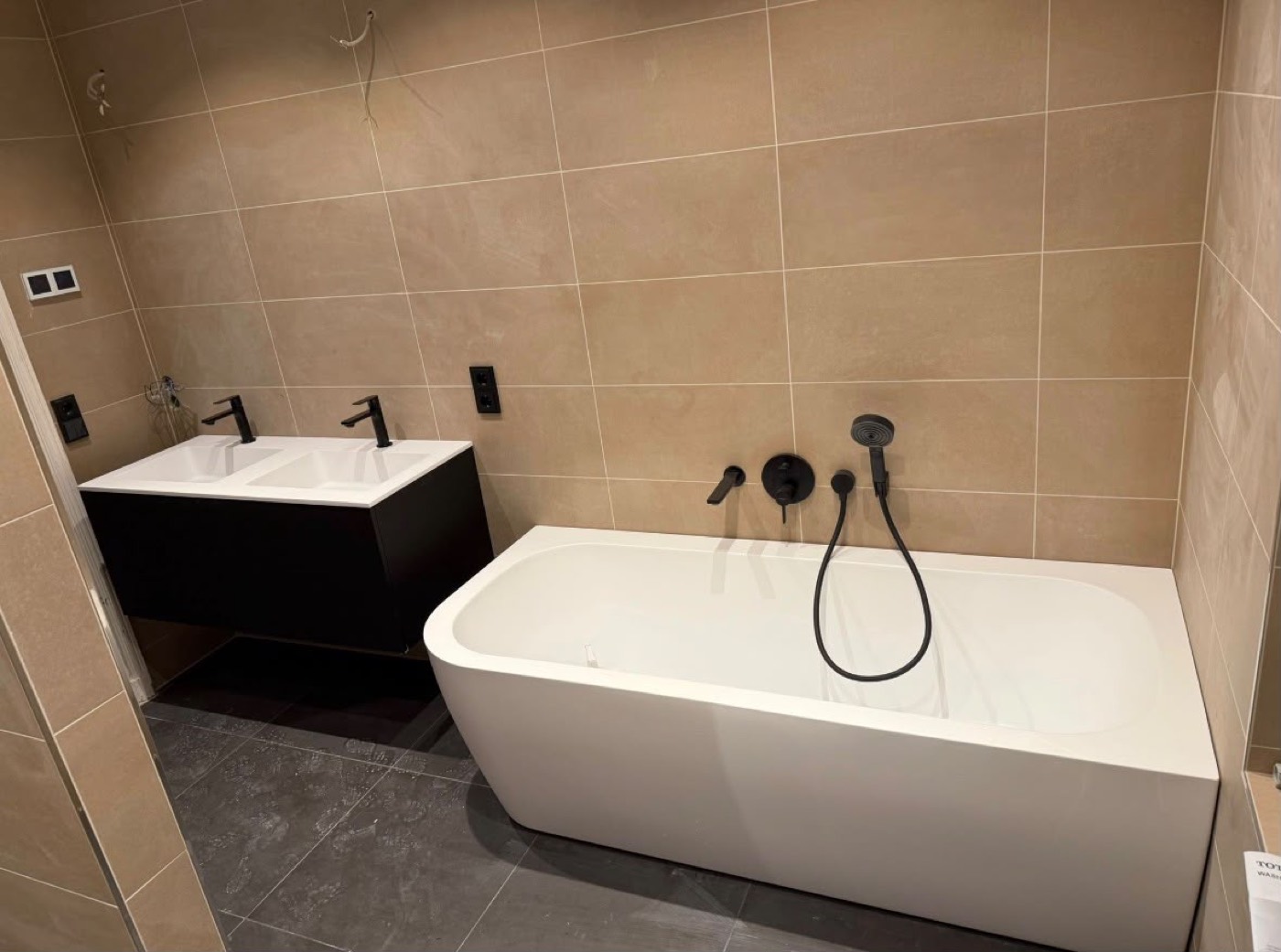 Freistehende Badewanne mit schwarzer Armatur und Doppelwaschtisch