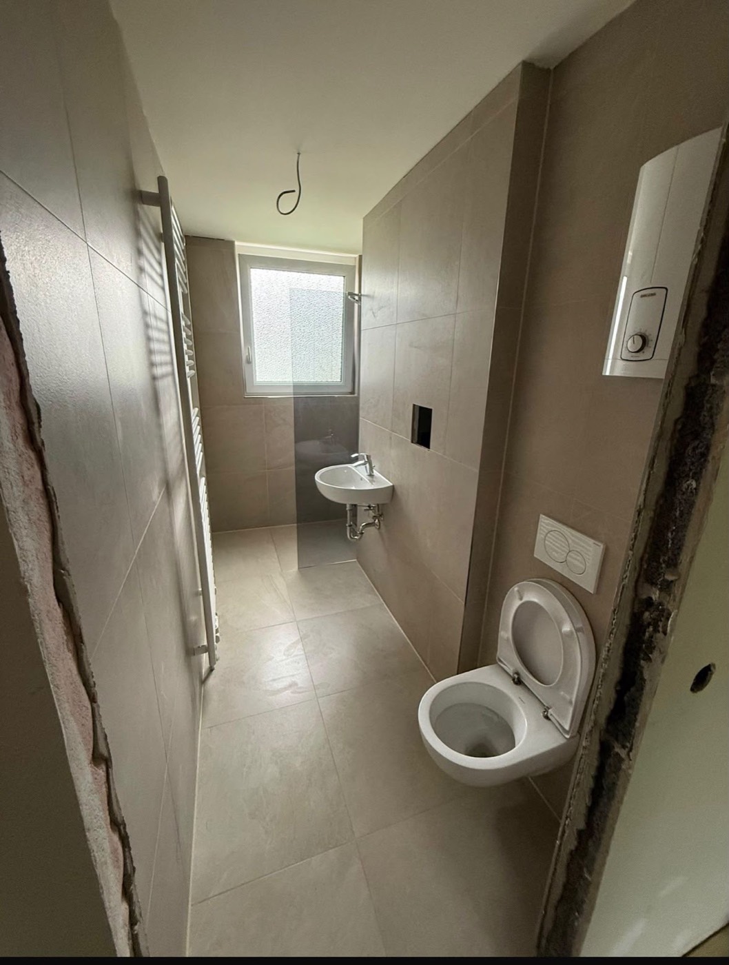 Neu gefliestes Bad mit Hänge-WC, Waschbecken und Durchlauferhitzer