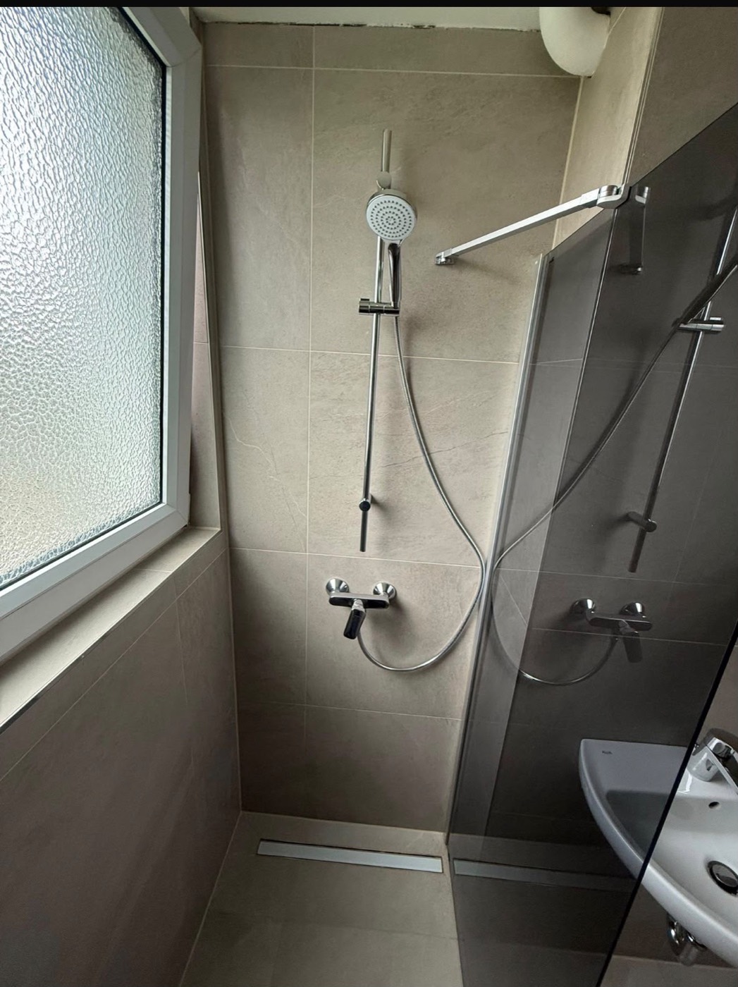 Bodengleiche Dusche mit Glastrennwand und Edelstahl-Duschrinne