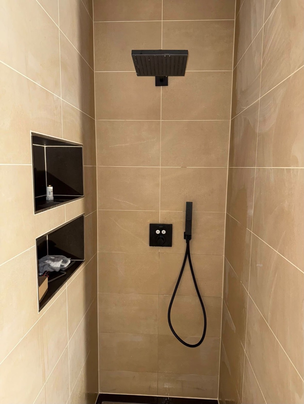 Begehbare Dusche mit schwarzer Regenbrause und beleuchteten Wandnischen